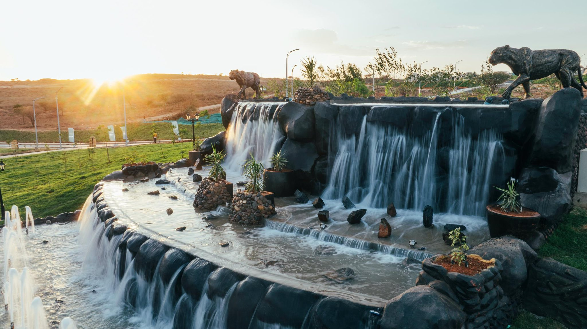 The leopard waterfall at golden hour, sculptures prowling the rocks
