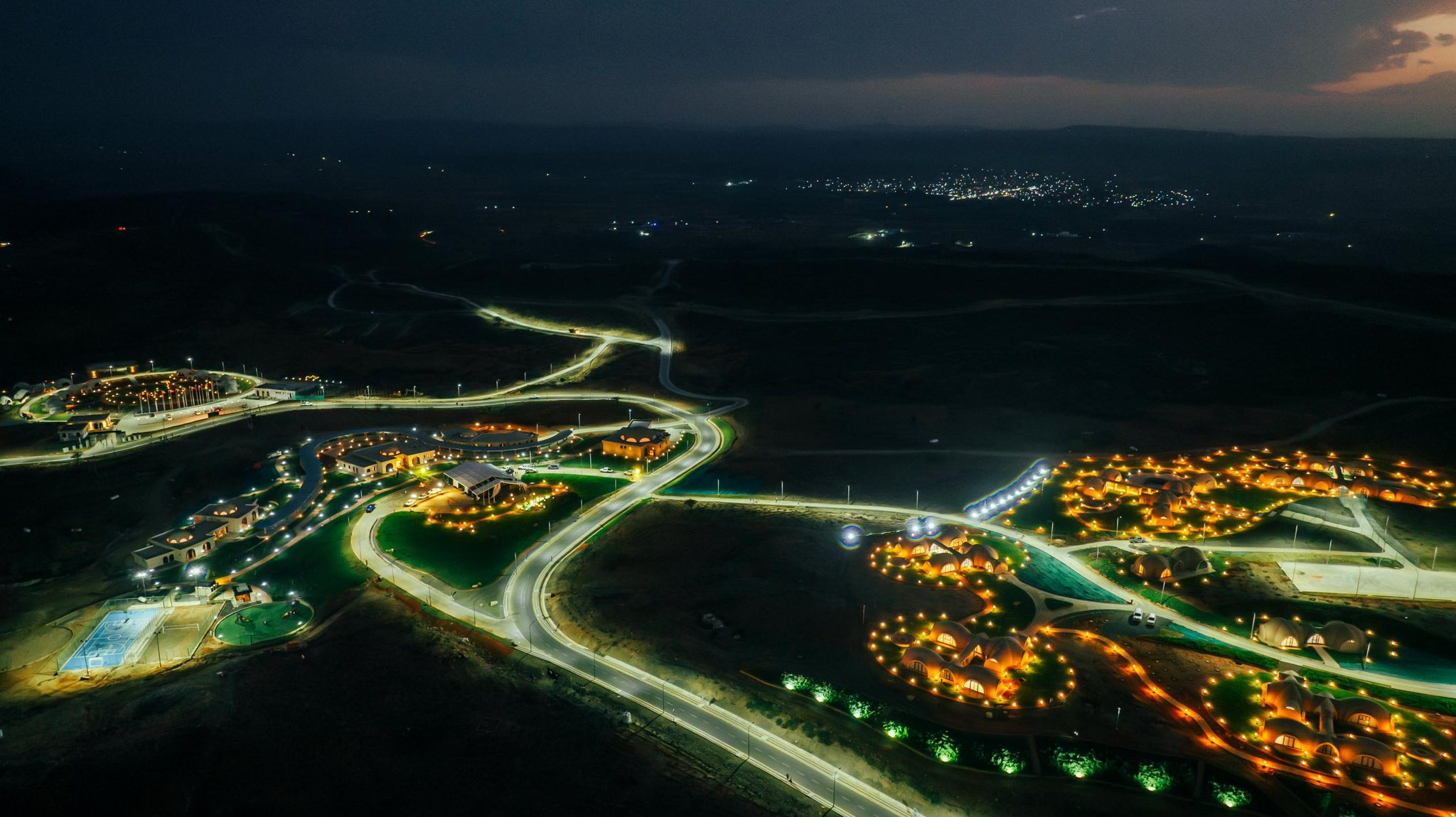 Shabeelay at deep dusk, lights winding through dark highland terrain