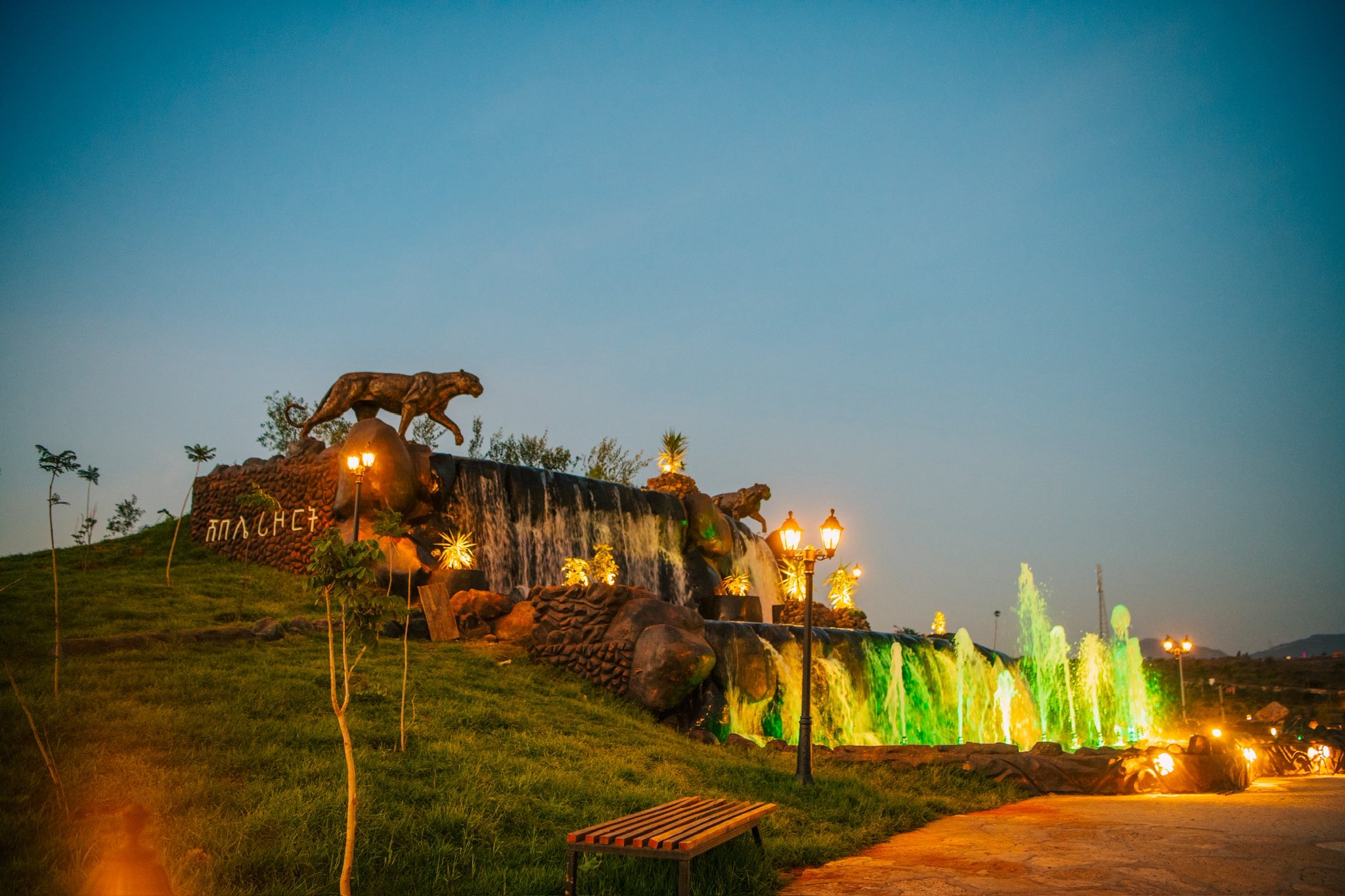The leopard fountain at blue hour, water lit green and gold beside the dining terraces